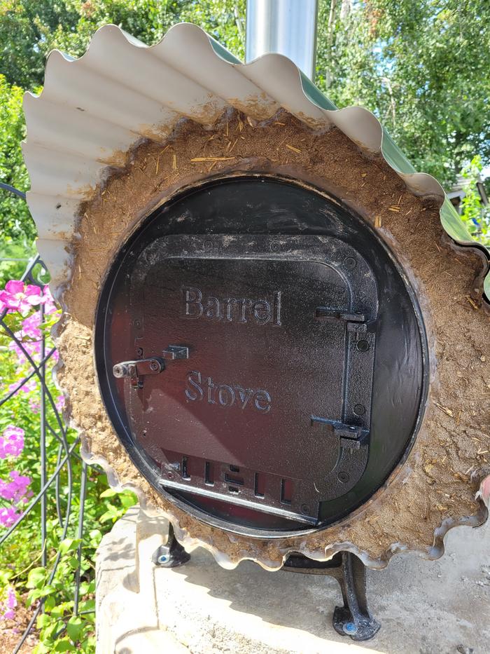 A barrel stove door in the back of a rocket oven