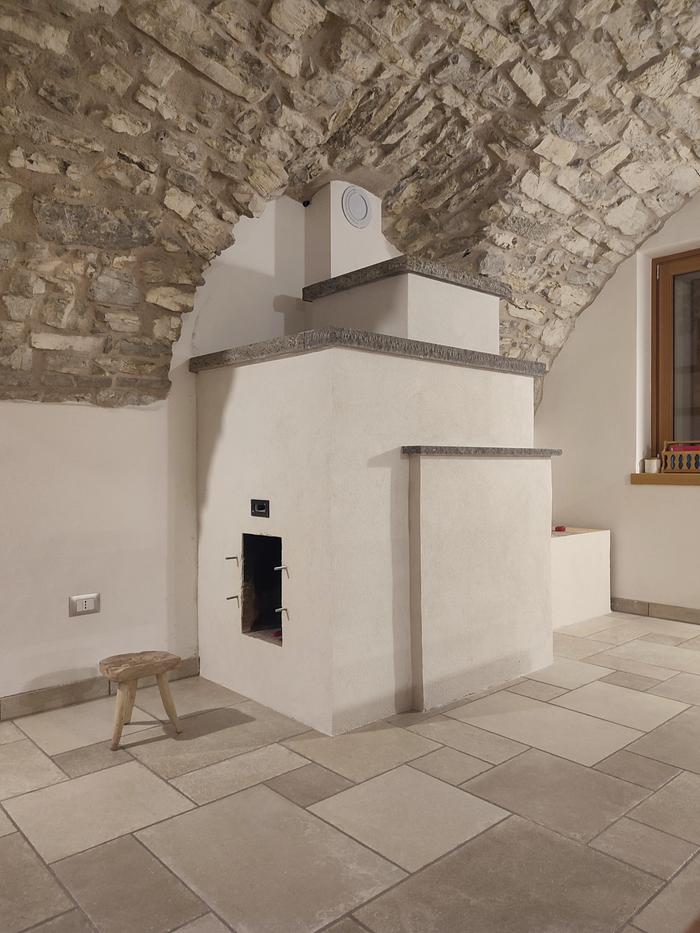 rocket mass heater with plaster in a stone house with a tiled floor