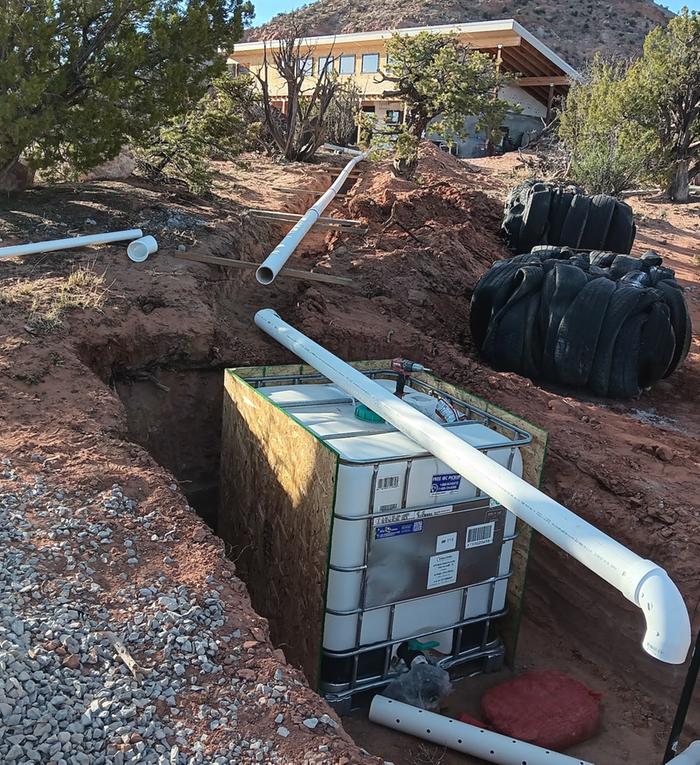 IBC tote in a pit with PVC pipes for a worm bin septic system