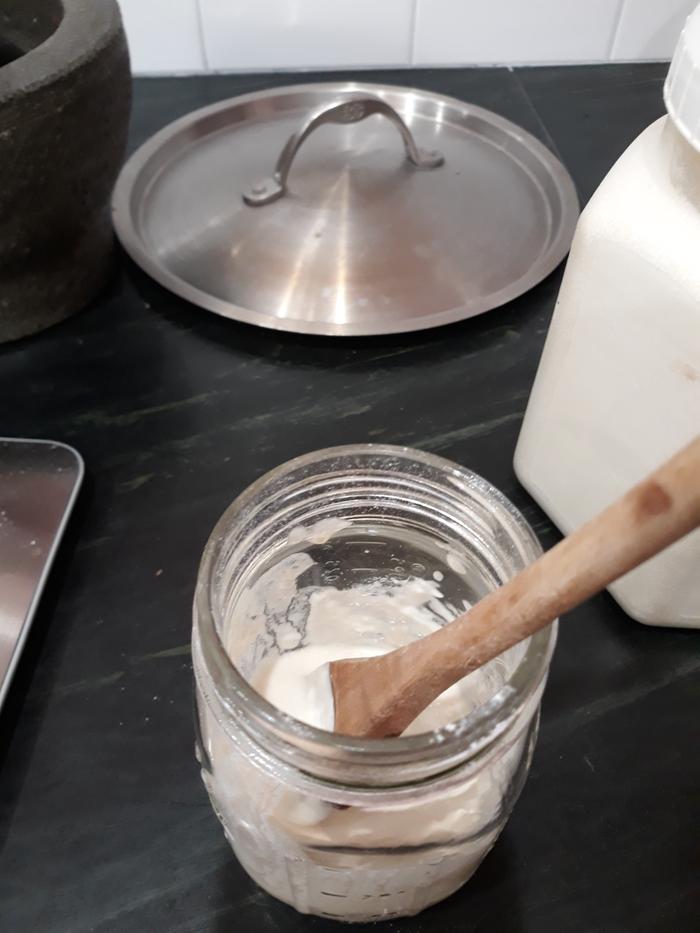 mixing sourdough starter with a wooden spoon