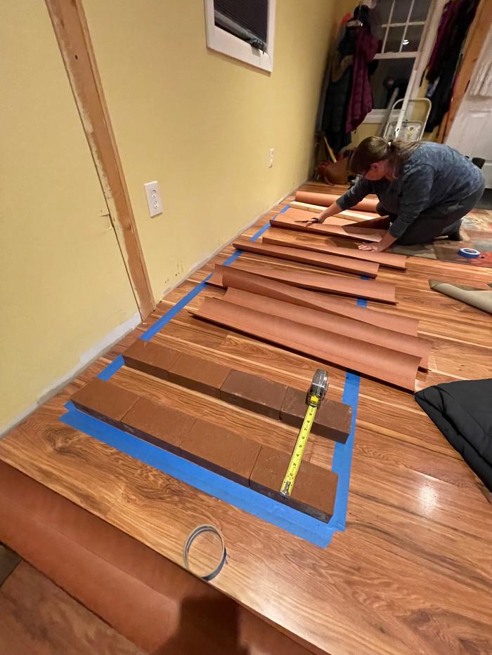 Laying rocket mass heater foundation bricks for heating channels on a suspended floor.