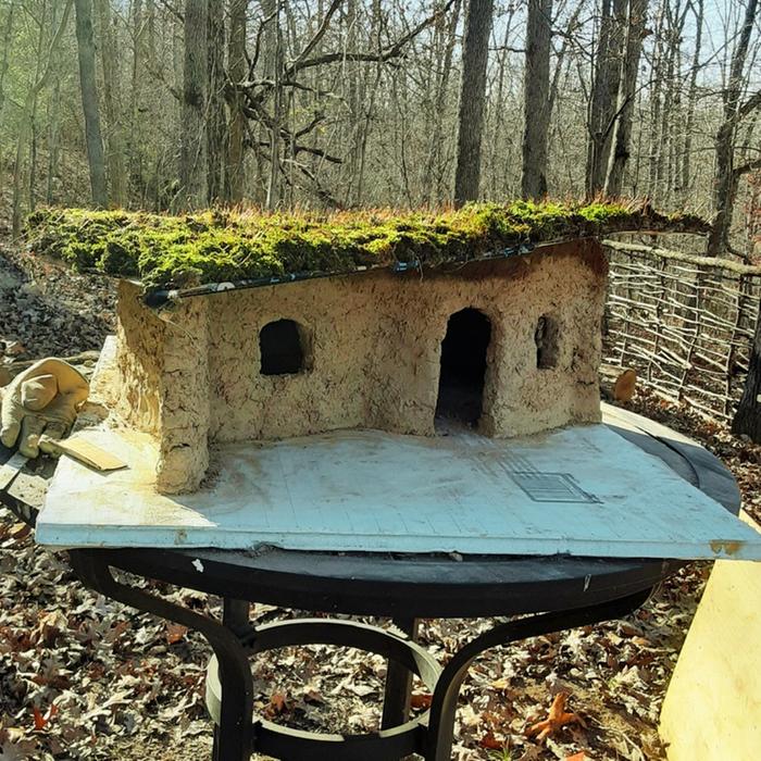 model of a cobbed house with a green roof