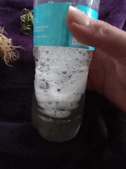 Soapy bubbles in a water bottle after violet roots were added