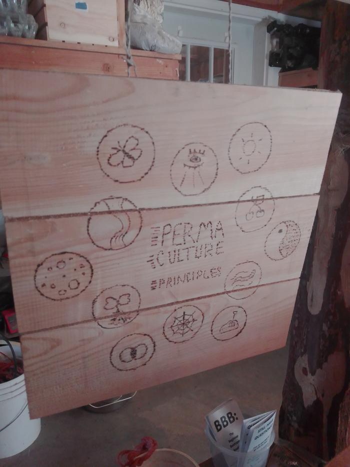 woodburned sign of the permaculture principles includhing observation