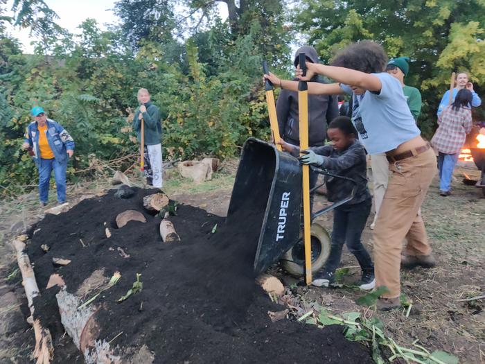 Duping dark mulch on a garden bed in a community garden in Minnesota