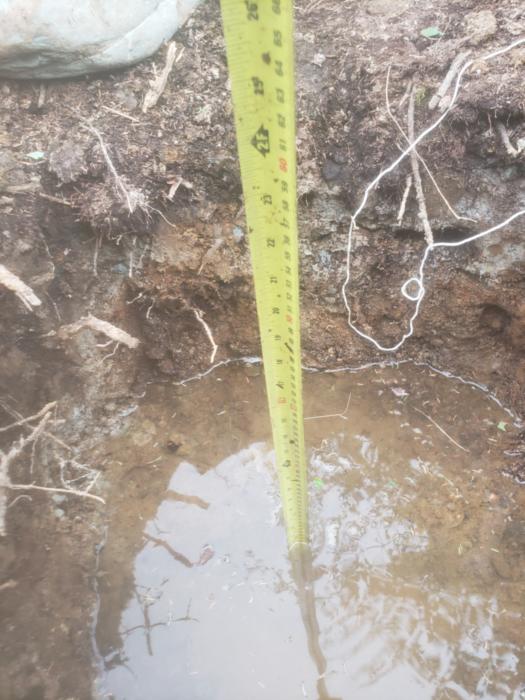 A measuring tape in muddy water in a hole