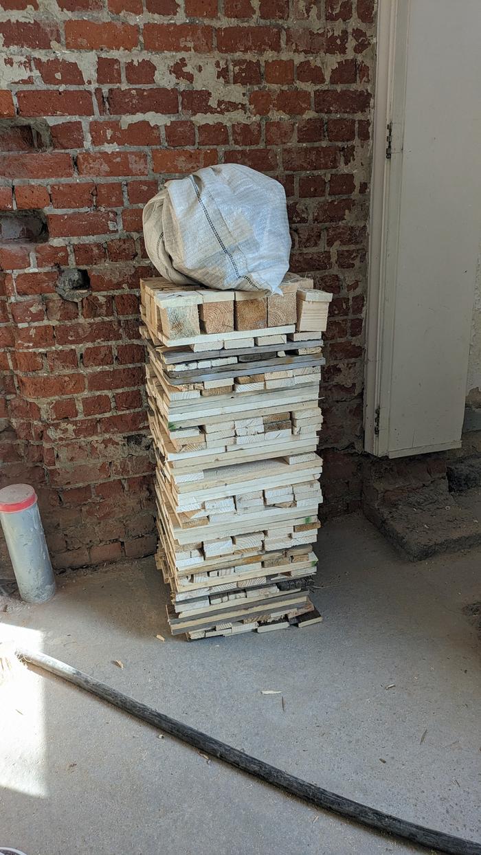 The pile of wood with some small kindling in a bag on top