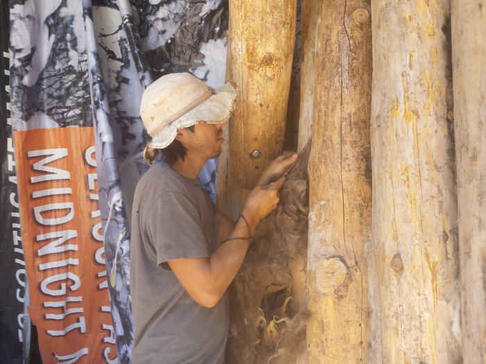 Fred stuffing wool into the wall for insulation.
