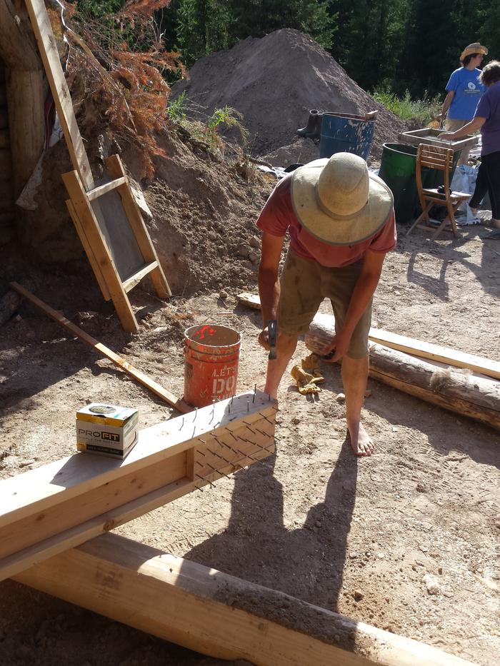 Evan preparing the door catch beam for burial. The nails will help hold it in place.