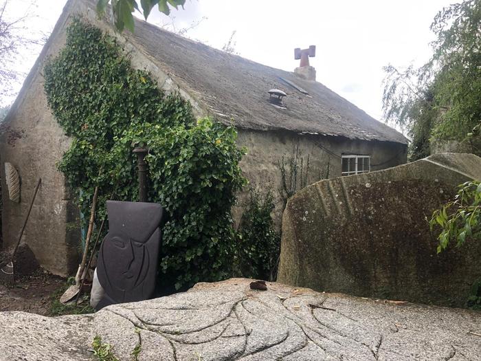 Exterior view of a stone cottage with a rocket mass heater in it