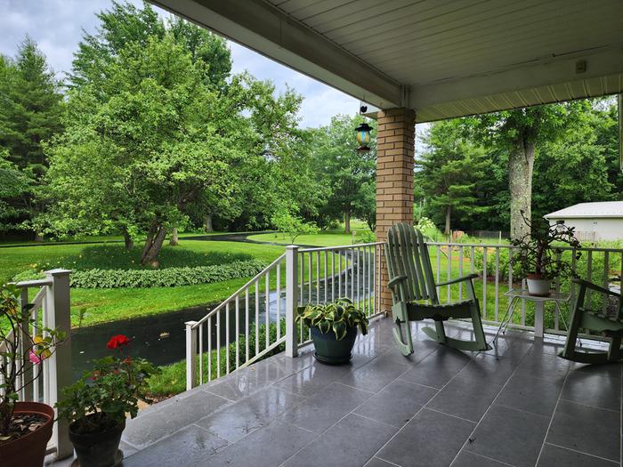 A big front porch with tile floor, brick column and rocking chairs