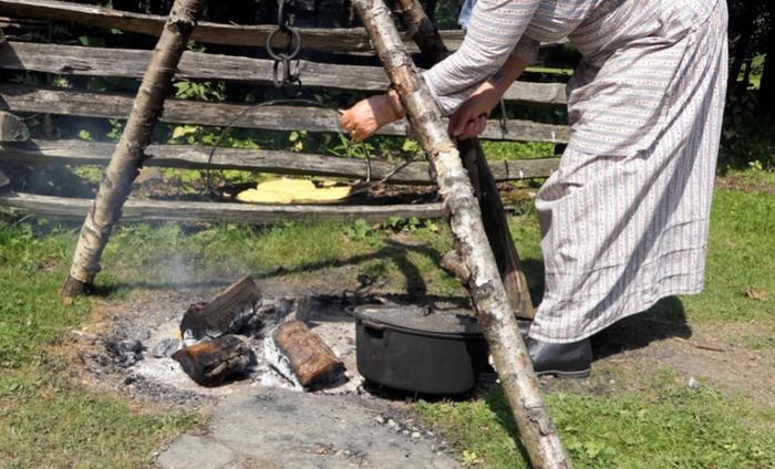 historical reenactor baking pancakes over a wood fire