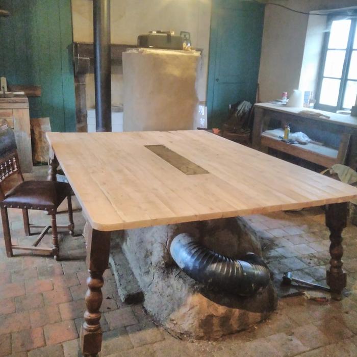 kitchen table with a rocket masonry heater underneath it