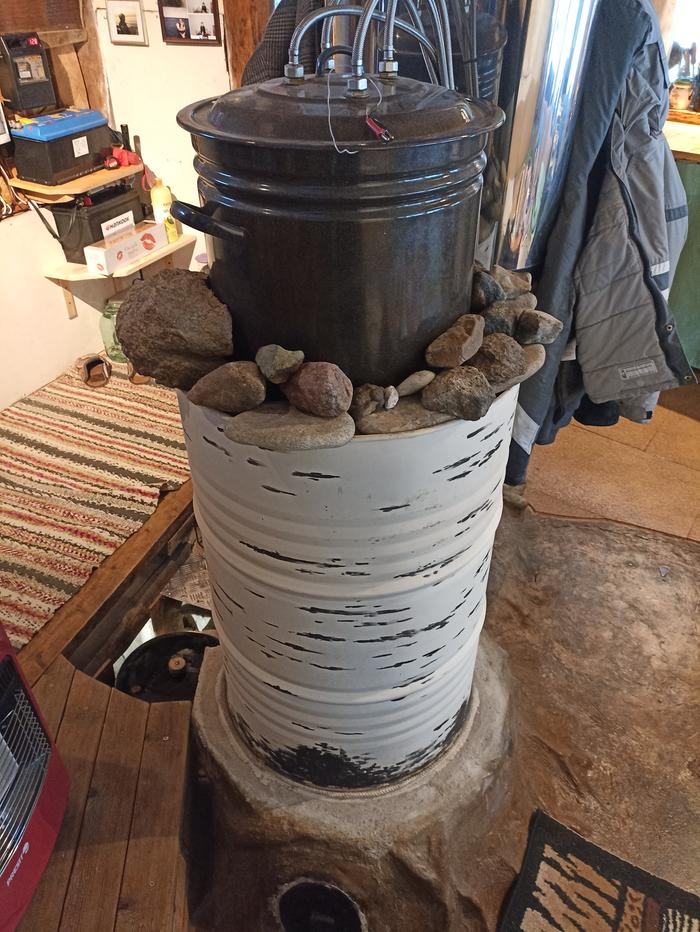 a water heater made from a canner on top of the barrel of a rocket masonry heater in Estonia