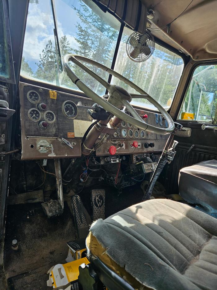 inside the cab of a dumptruck with guages and a ripped seat