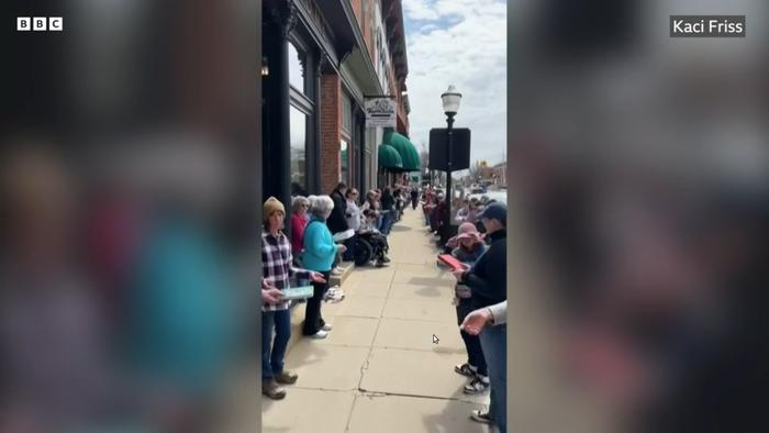 freeze frame from a video of a human chain moving books about a block away