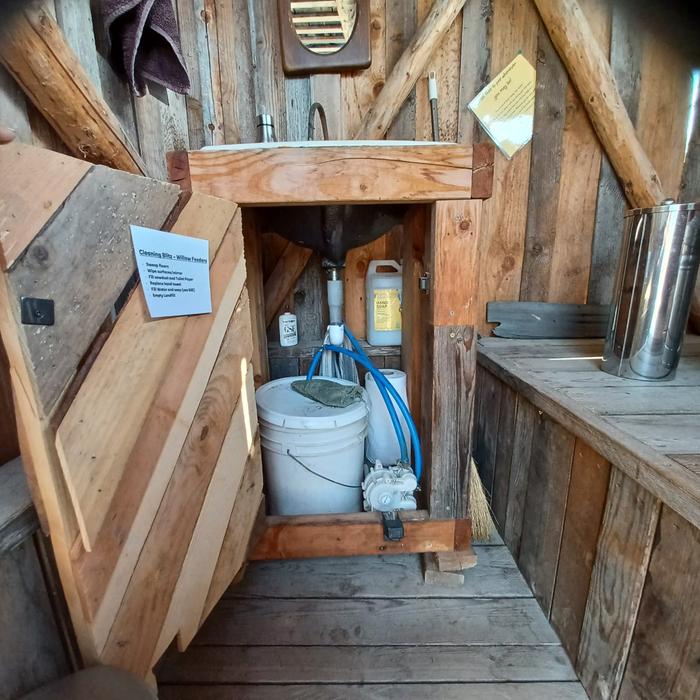 the plumbing of the sink in willowonka with a bucket of fresh water and some hoses that feed the foot pump