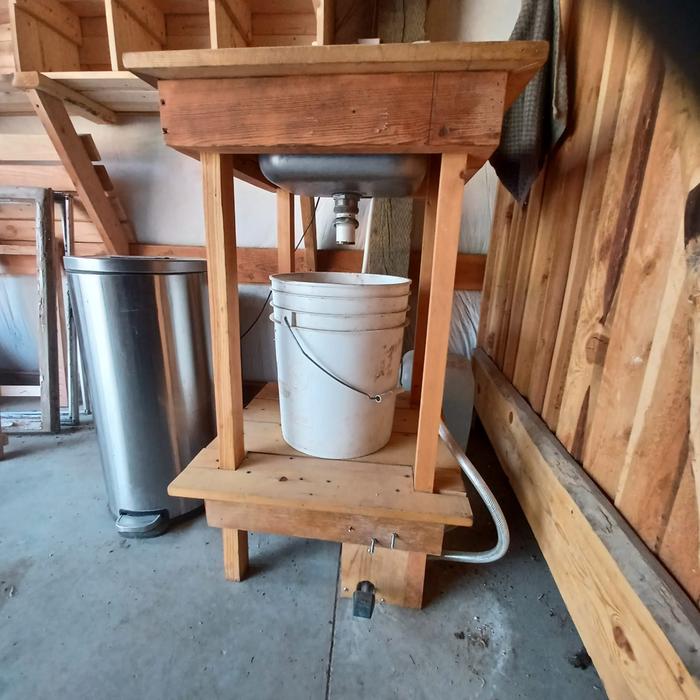 A standalone portable foot pedal operated sink with a bucket in the classroom