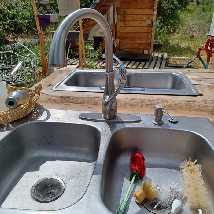 outdoor sink in a natural wood counter with an assortment of scrub brushes