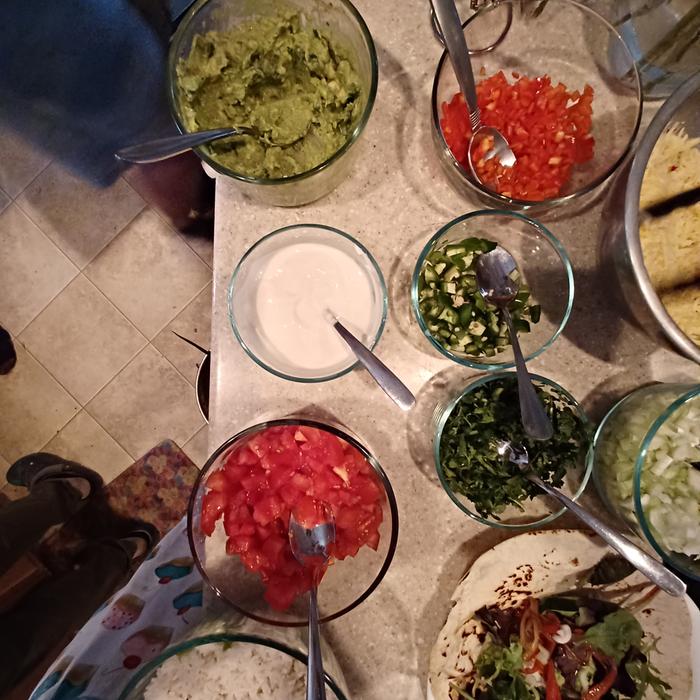 salsas, guacamole, onions and other taco topping on a table