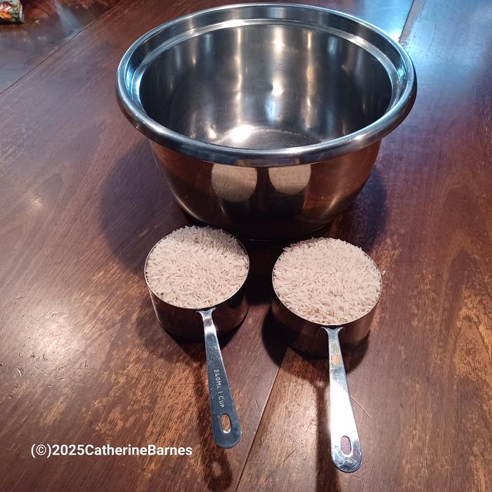 2 cup measures in front of a rice cooker bowl