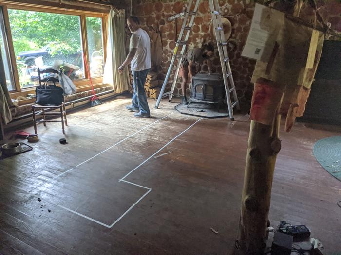 Two men removing an old woodstove so that a rocket masonry heater may be installed