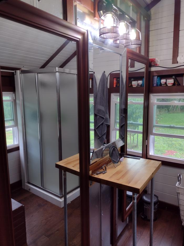 Bathoom with floor length mirrors, shelving, and hot shower