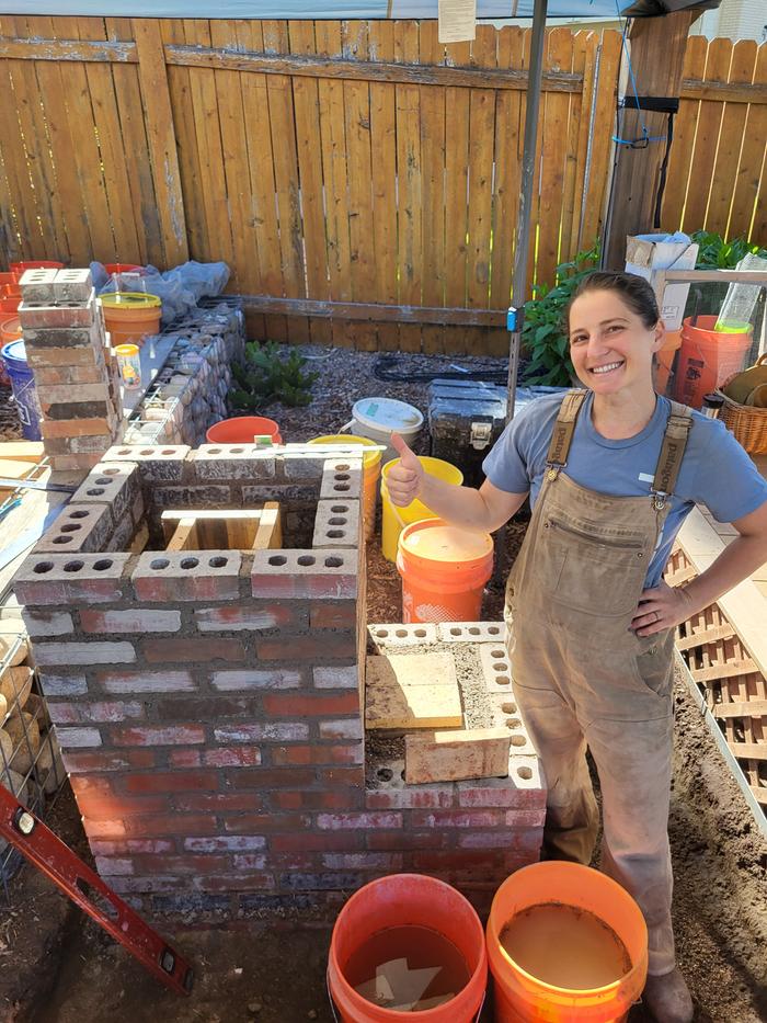 Alexandra rebuilding her rocket oven in a friend's backyard