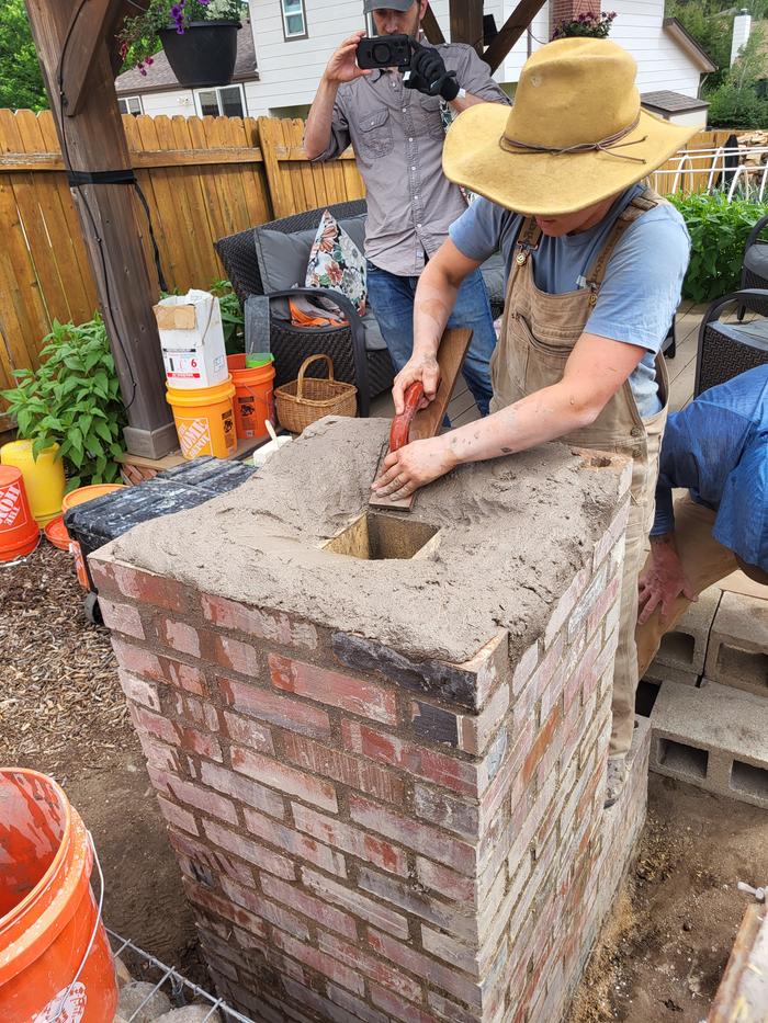 Alexandra shaping mud to hold up the oven
