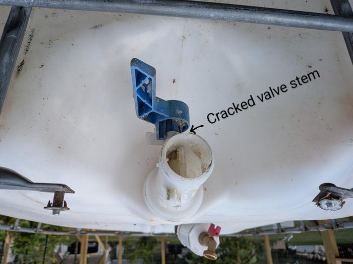 Photo of the valve on the bottom of an IBC tote, arrow pointing to cracked stem.