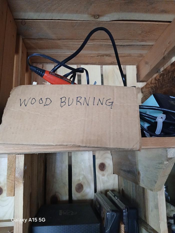 a box of wood burning tools on a wooden shelf