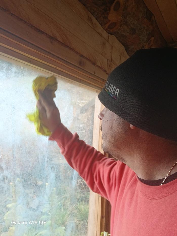 Esteban cleans a window with a yellow rag