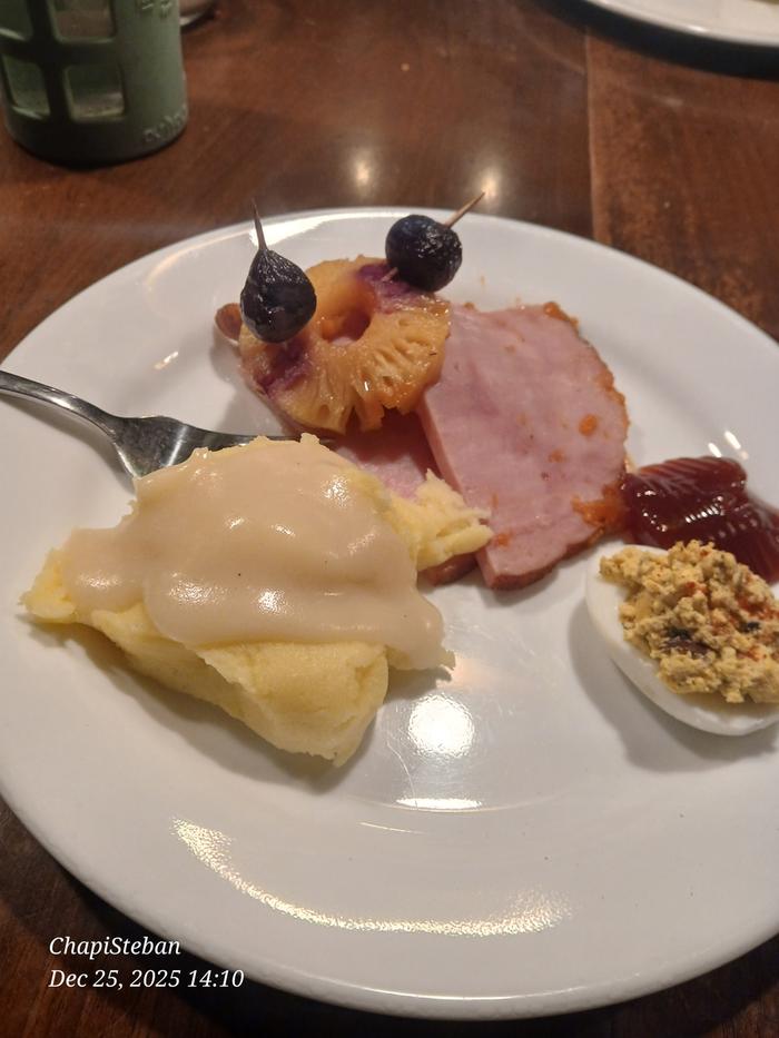 Christmas dinner of ham, mashed potatoes, deviled eggs, pineapple and cranberry sauce on a white plate
