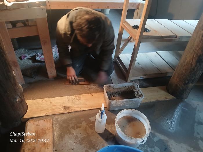 Harry applies fresh cob to a floor with plastic tubs and a spray bottle