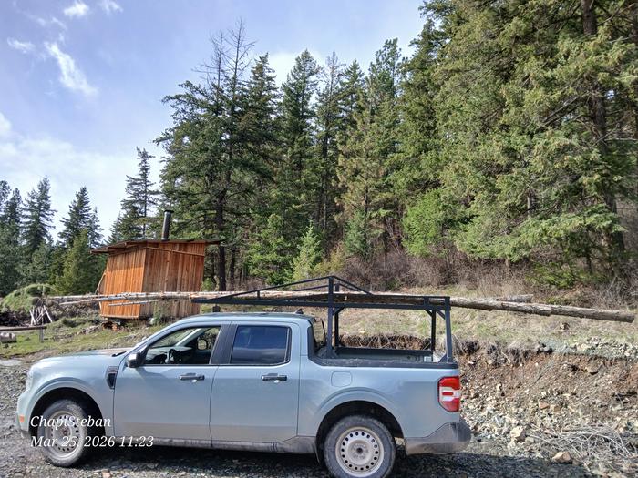 a truck with junkpoles on its ladder rack in front of a skiddable cabin