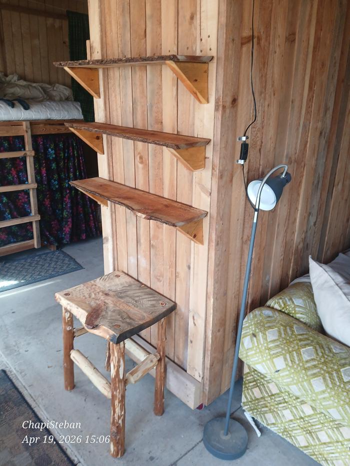Three wood shelves and a stool in the solarium