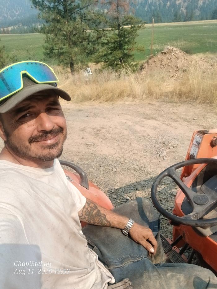 Esteban sitting on a tractor on a gravel road in Montana
