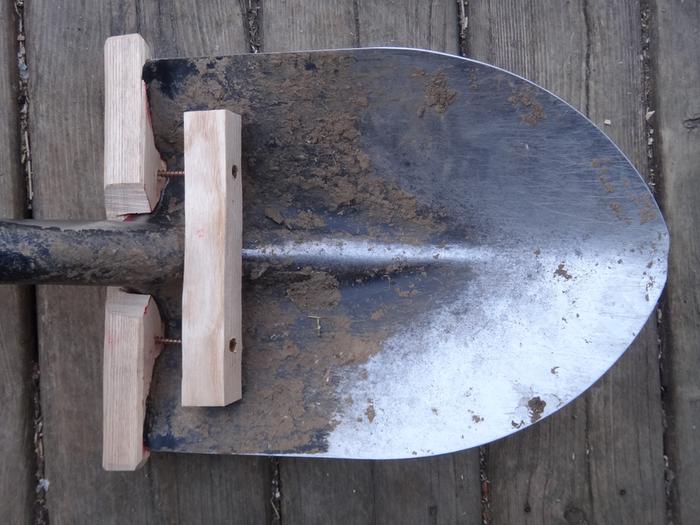 A wooden step clamped onto a shovel so that you can dig with bare feet