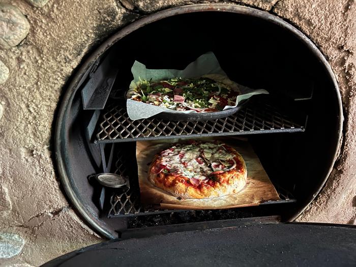pizza cooking in barrel oven