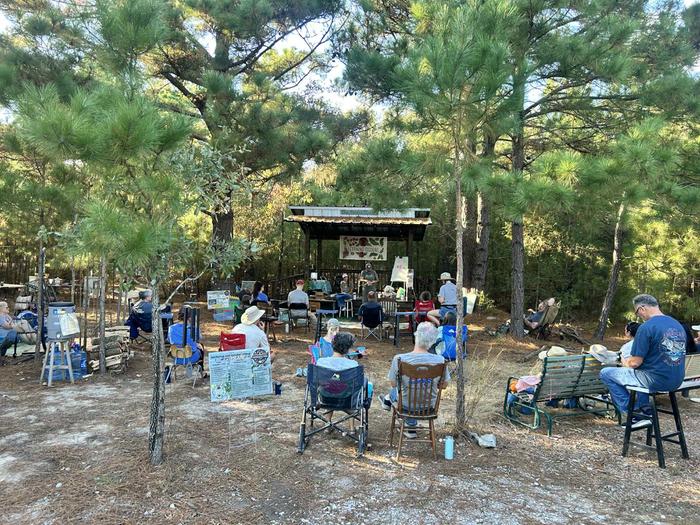 People sit and learn about homesteading at the Texas Permaculture Convergence in an outdoor classroom