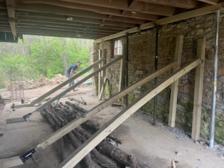 Our pushing setup. The bottle jacks were pressing against a 2x6 that we anchored to the concrete slab. We cut little wooden cleats so that they would be pressing onto their respective posts (and therefore the wall) at a good angle/height