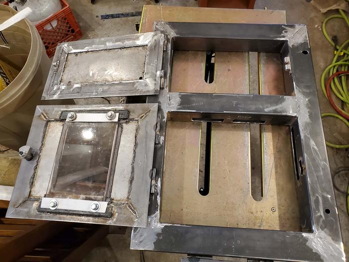 Fireglass held in by bolts and washers screwed into threaded holes. Door handle wedge-locks as it's turned. Oven door and air flap use marine grade cabinet latches.