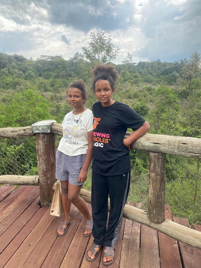 two girls in sandals standing on a rustic balcony