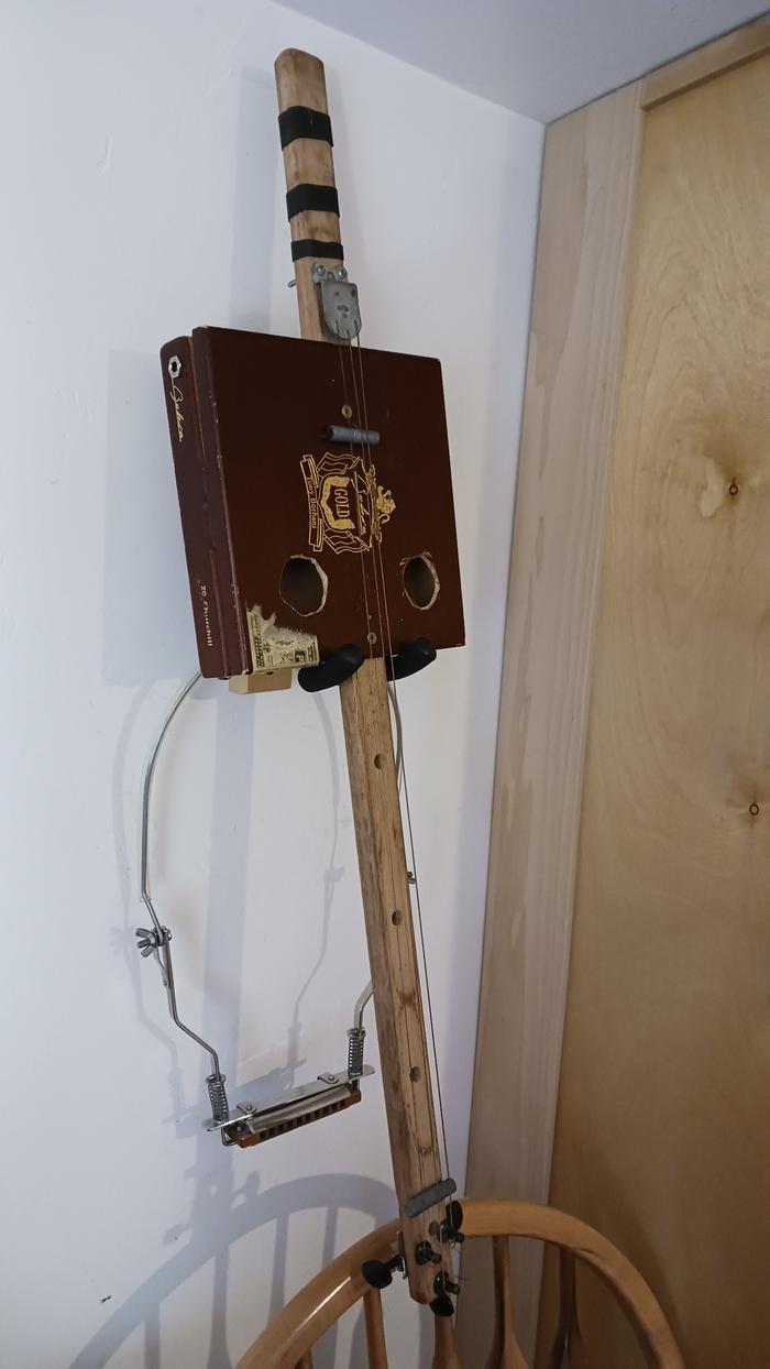 My cigar box guitar hanging on the wall with my harmonica