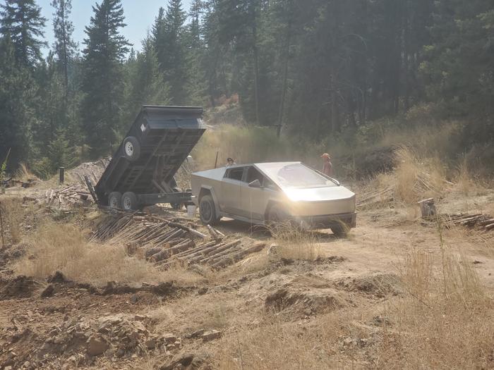 a cyber truck with a dump trailer delivering sand to a new hugel. Turn sand into soil with hugelculture!