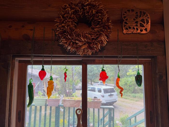 Glass chiles hanging below a ristra/wreath of cayennes