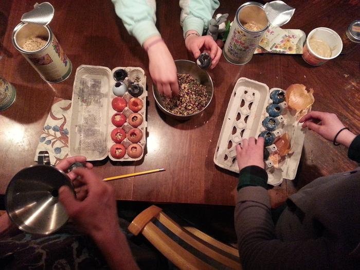 Many hands filling confetti eggs with seed