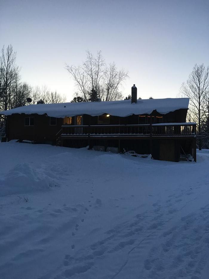 the log home in a heavy winter snow, as seen from the pasture