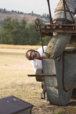 paul wheaton in lab coat mad scientist, hiding behind rusty farm equipment