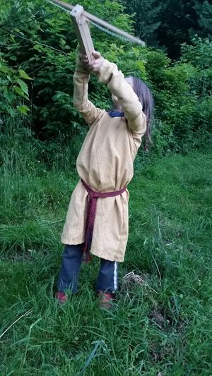 boy with crossbow in gold medieval tunic with keyhole neck